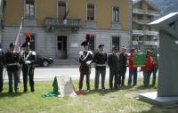 Carabinieri, Finanzieri e agenti della Polizia di Stato schierati a guardia d'onore presso il cippo dedicatorio. 
A sinistra si